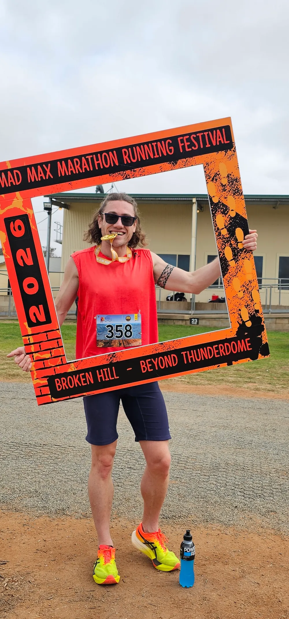 Eli holding his winner's medal in his teeth inside the Mad Max Marathon Running Festival photo frame